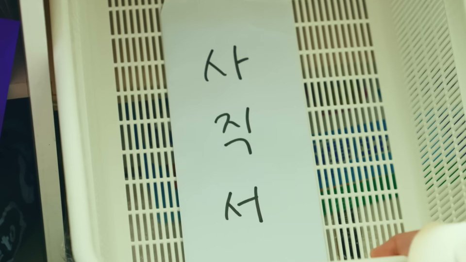 흰 플라스틱 바구니 안에 세워 둔 흰 봉투에 검은 손글씨로 「사 직 서」가 세로로 적힌 장면